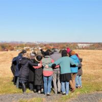 A group huddled closely on the top of Freshkills Park.